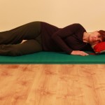 Lying on side with bottom knee drawn in towards chest, top leg long, for start of exercise